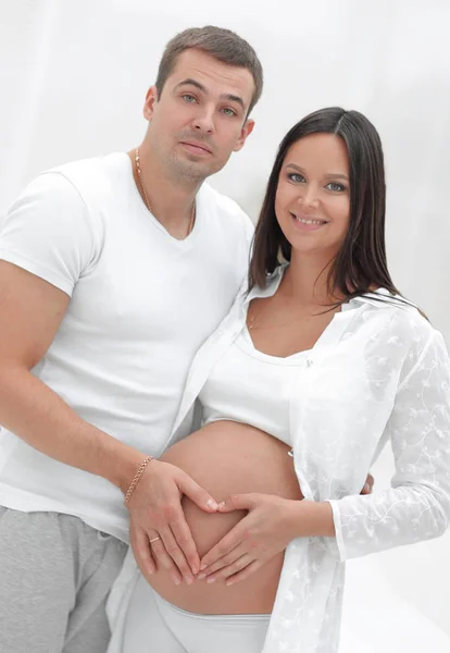 Karnı üzerinde kalp şeklinde katlanmış elleri olan hamile bir kadın ve koca. — Stok fotoğraf