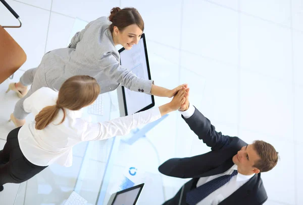 Vista a partir do topo. Membros da equipe de negócios dando uns aos outros um alto cinco acima da mesa . — Fotografia de Stock