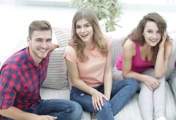 Grupp av glada vänner titta på videor, sitter i soffan — Stockfoto