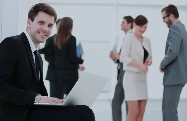 Retrato de un hombre de negocios sonriente sentado con compañeros de trabajo en —  Fotos de Stock