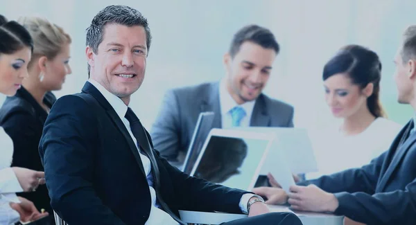 Portrait of mature business man smiling during meeting with colleagues in background — Stock Photo, Image