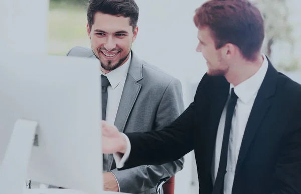 Homens de negócios sorridentes mostrando algo no computador como colega — Fotografia de Stock