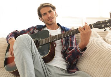 oturma odasında kanepede oturup gitar ile Modern adam.