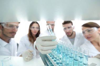 arka plan görüntüsü sıvı cam tüp içinde eğitim microbiologists oluşan bir gruptur.