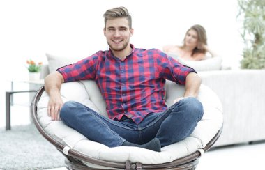 arka plan bulanık bir büyük yuvarlak sandalyede oturan modern genç adam