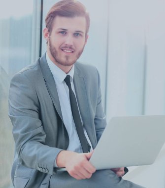 Ofiste dizüstü bilgisayarla çalışan yakışıklı iş adamı.