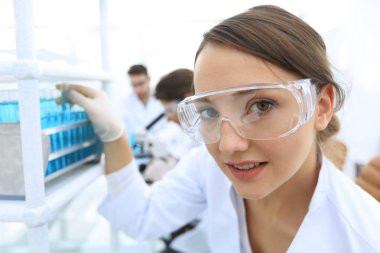 Genç kadın bilim adamı test tüpleri tutarak koruyucu gözlük