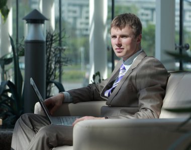 Masasının üzerindeki laptop ile ofisinde çalışan iş adamı.