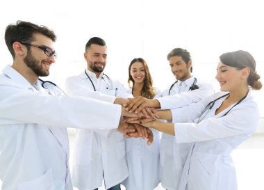 Doktorlar ve hemşireler tıbbi bir ekipte el ele tutuşuyorlar.