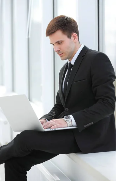 Jovem profissional com laptop no fundo da janela do escritório — Fotografia de Stock