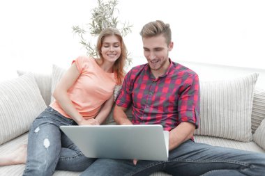 Mutlu modern çift internette sörf yapıyor ve evde dizüstü bilgisayarla çalışıyor.