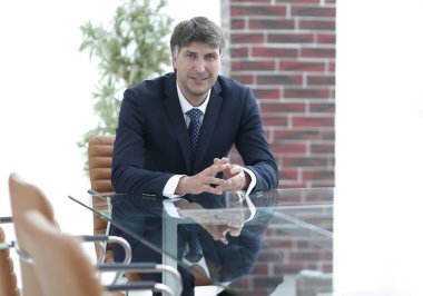 Bir boş konferans salonunda bir masada oturan proje yöneticisi