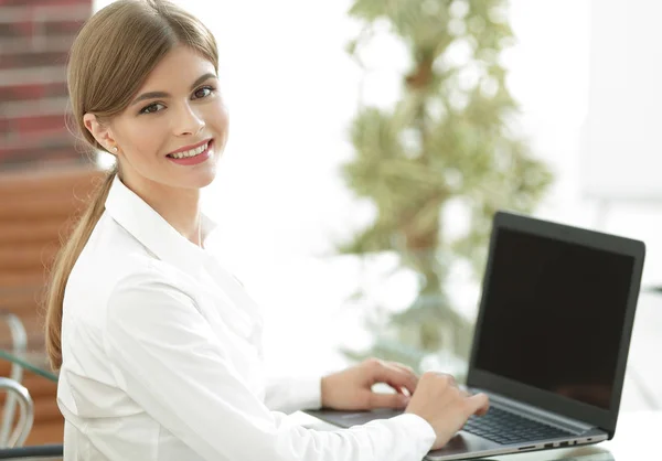 Joven mujer de negocios sentada en su escritorio en una oficina, trabajando en una computadora portátil —  Fotos de Stock