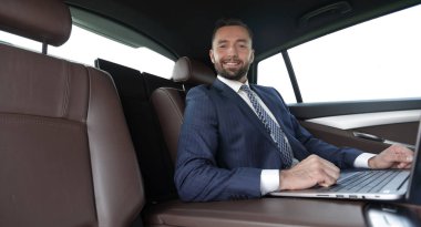 başarılı adam arabanın içinde otururken dizüstü bilgisayar ile çalışma