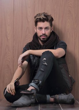 Sıradan giyinmiş sakallı bir adam oturur.