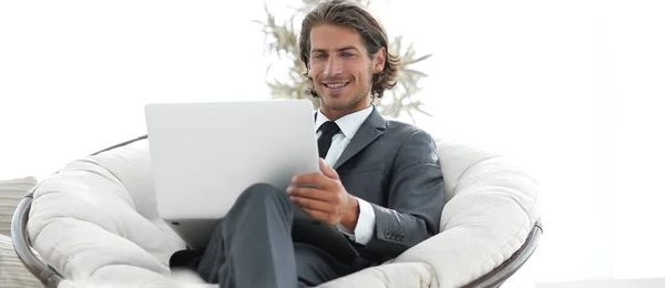 Succesvolle zakenman met laptop zitten in een grote comfortabele armchai — Stockfoto