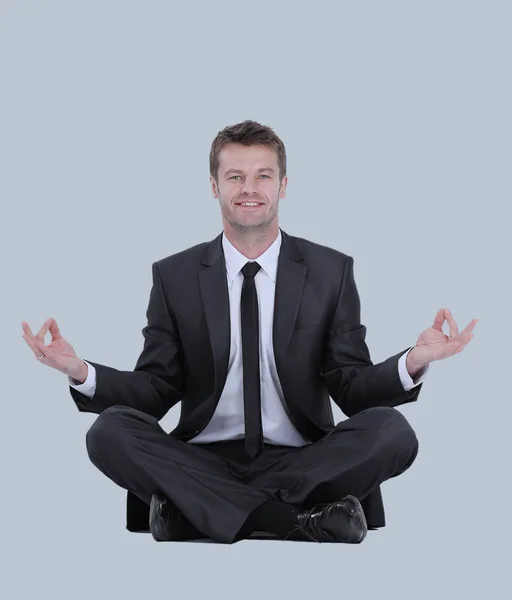 Calm businessman sitting in lotus pose on gray background — Stock Photo, Image