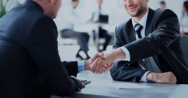 Toplantı sırasında iki iş arkadaşı el sıkışıyor.