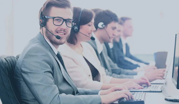 Aantrekkelijke jonge man aan het werk in een callcenter met zijn collega 's — Stockfoto