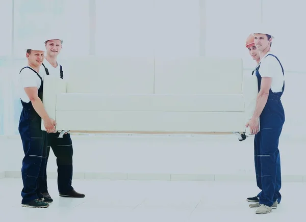 Щасливі чоловіки рухаються в уніформі, що несе білий диван — стокове фото