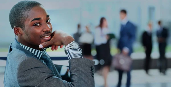 Portrait d'un homme d'affaires afro-américain souriant avec des cadres travaillant en arrière-plan — Photo