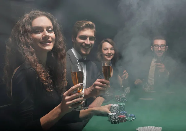 Grupo de amigos sentados en la mesa de juego en el casino —  Fotos de Stock