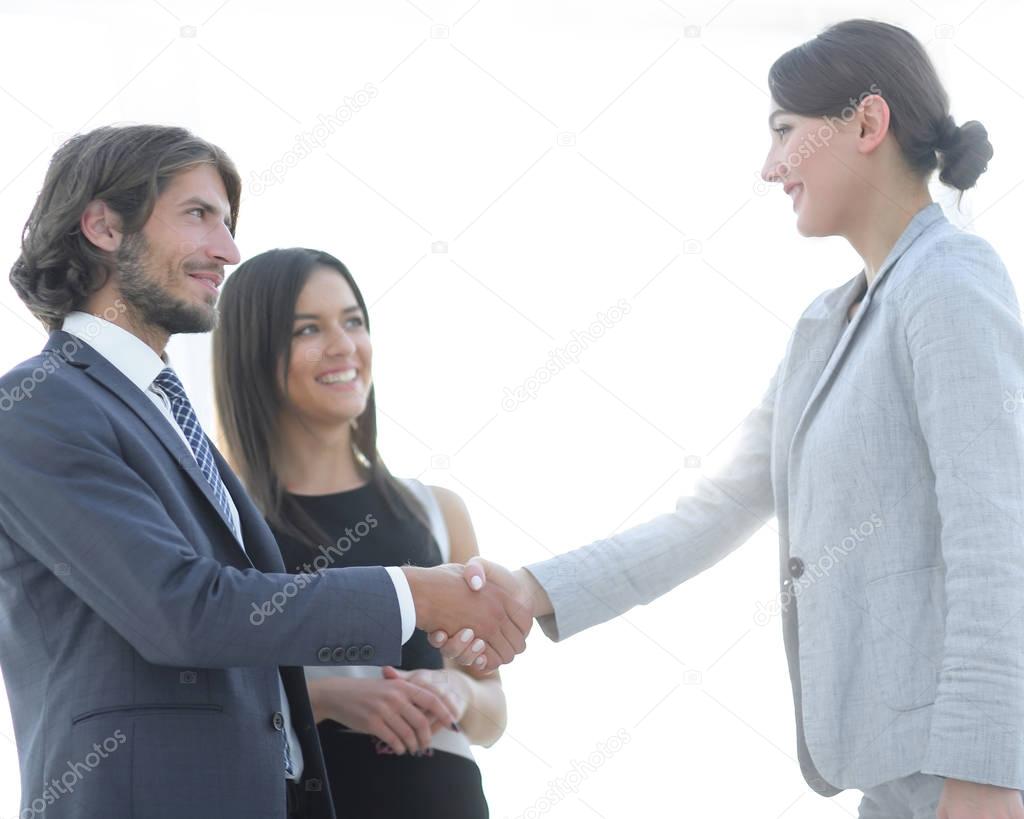 Businesspeople  shaking hands against room with large window loo