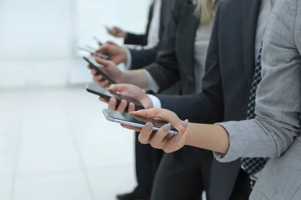 Group of people look at phones in arms at office closeup.