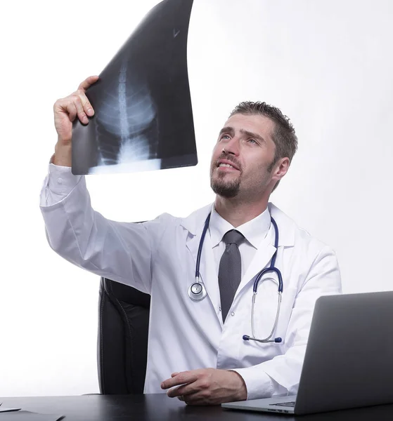 Ο γιατρός εξετάζει ένα x-ray, που κάθεται πίσω από ένα γραφείο — Φωτογραφία Αρχείου