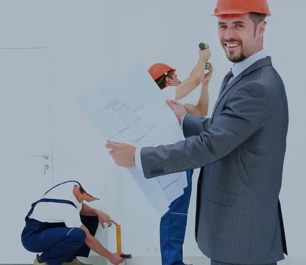 Engineer studying blueprints against the backdrop of a team  b — Stock Photo, Image