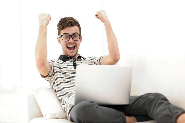 Счастливый человек с ноутбуком, сидящий на диване — стоковое фото