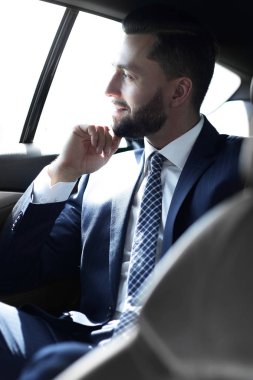 Bir arabanın arka koltuğunda oturan gülümseyen iş adamı