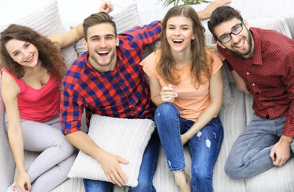 Cuatro amigos felices riendo mientras están sentados en el sofá —  Fotos de Stock