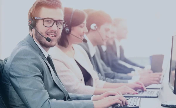 Aantrekkelijke jonge man aan het werk in een callcenter met zijn collega 's — Stockfoto