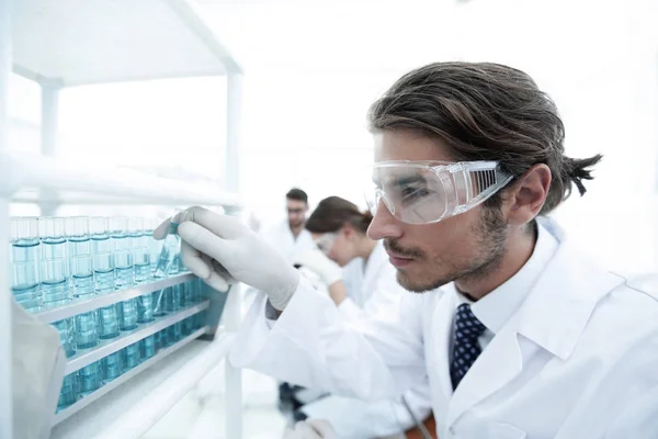 Assistente de laboratório em óculos e jaleco com tubo de ensaio — Fotografia de Stock