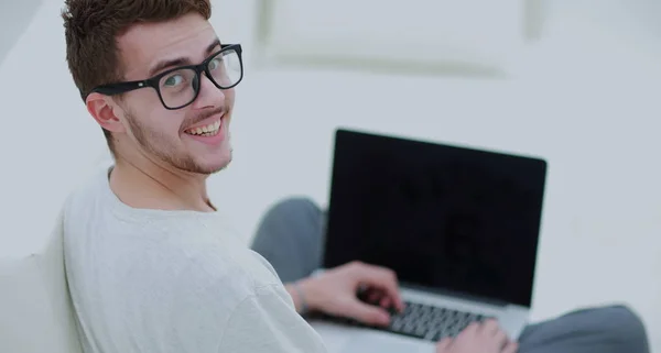 Vue arrière du jeune homme utilisant son ordinateur portable dans le salon lumineux — Photo