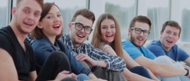 Bir grup üzerinde bir pencere pervazına oturan ve gülümseyen mutlu öğrenci