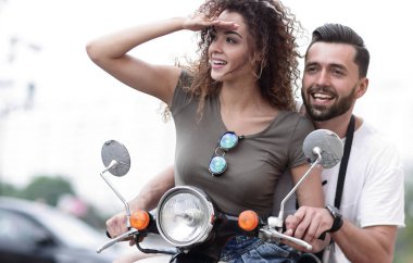 Güzel genç bir çift bir scooter sürme sırasında gülümsüyor