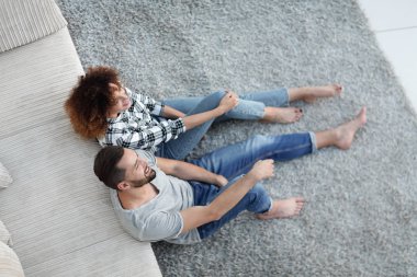 yeni bir oturma odasında bir halı üzerinde oturan yeni evli çift