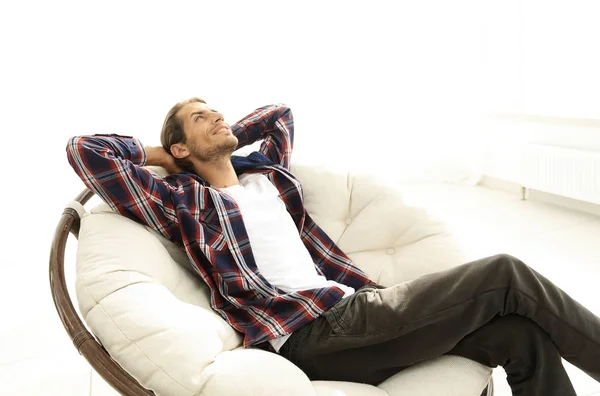 Chico serio descansa sentado y soñando en una silla cómoda grande . —  Fotos de Stock