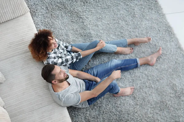 Newlywed couple sitting on a carpet in a new living room — Stock Photo, Image