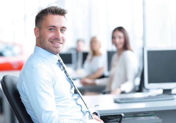 Succesvolle medewerker zittend achter een bureau en kijkend naar de camera. — Stockfoto