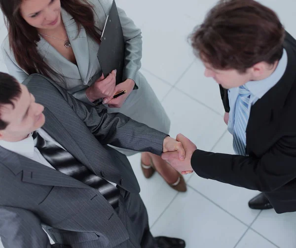 Two business people shaking hands and looking at each other with — Stock Photo, Image