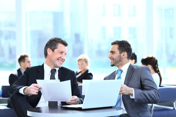 Parceiros de negócios discutindo um novo projeto, sentado no lobby do escritório. — Fotografia de Stock