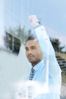 Camların arkasından manzara. Kendine güvenen iş adamı ofisinin penceresinden dışarı bakıyor.