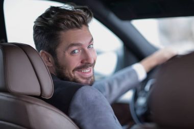 Dikiz aynası, genç adam arabasını sürüyor, kameraya bakıyor.