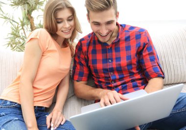 Mutlu modern çift internette sörf yapıyor ve evde dizüstü bilgisayarla çalışıyor.