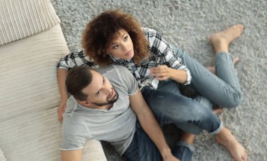 yeni oturma odasında halı üzerinde oturan genç Çift