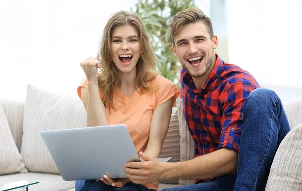 Jong koppel verheugt zich, zittend op de Bank tegenover de opengeklapte laptop — Stockfoto