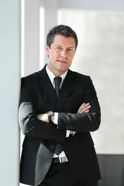 Hombre de negocios serio de pie cerca de la ventana en la oficina . — Foto de Stock